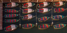 Four row of three red, white and green boats docked side by side on a body of water.