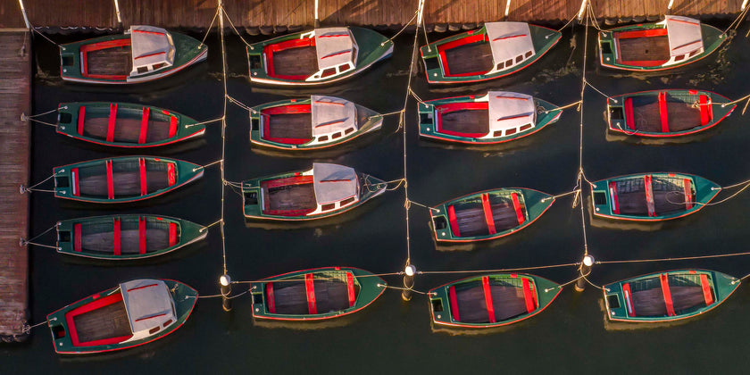 Four row of three red, white and green boats docked side by side on a body of water.