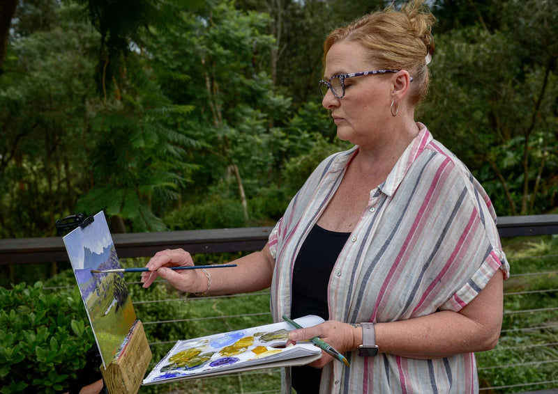 Artist painting outdoors with a natural background