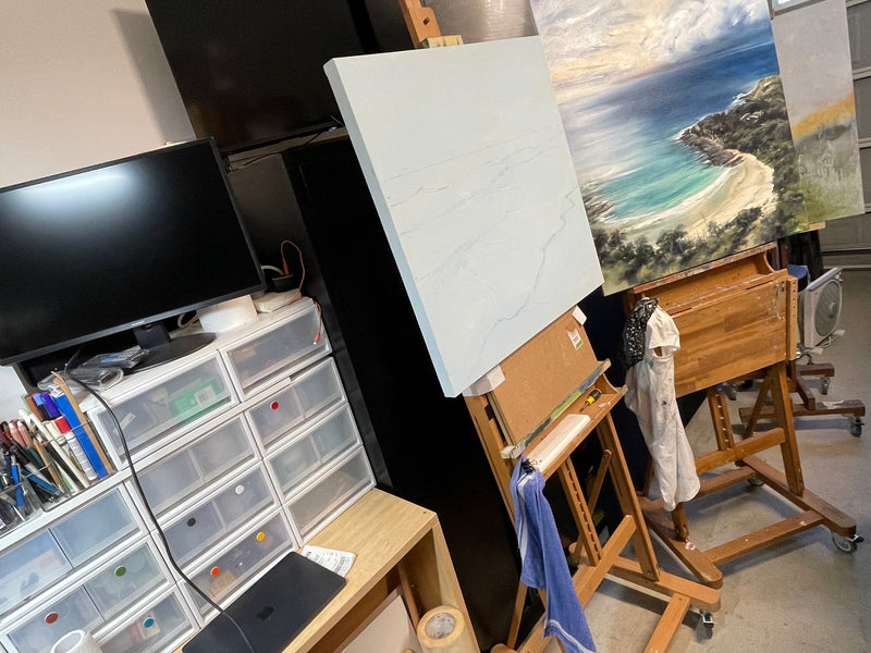 A coastal painting and a canvas in progress on easels in Geoff Barlow's studio