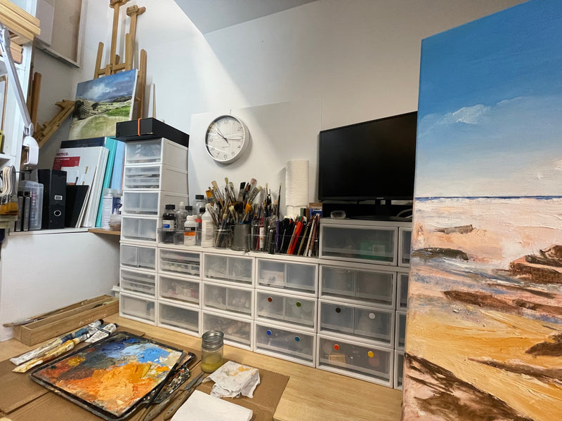 Geoff Barlow's studio workspace with palette, brushes and a coastal painting