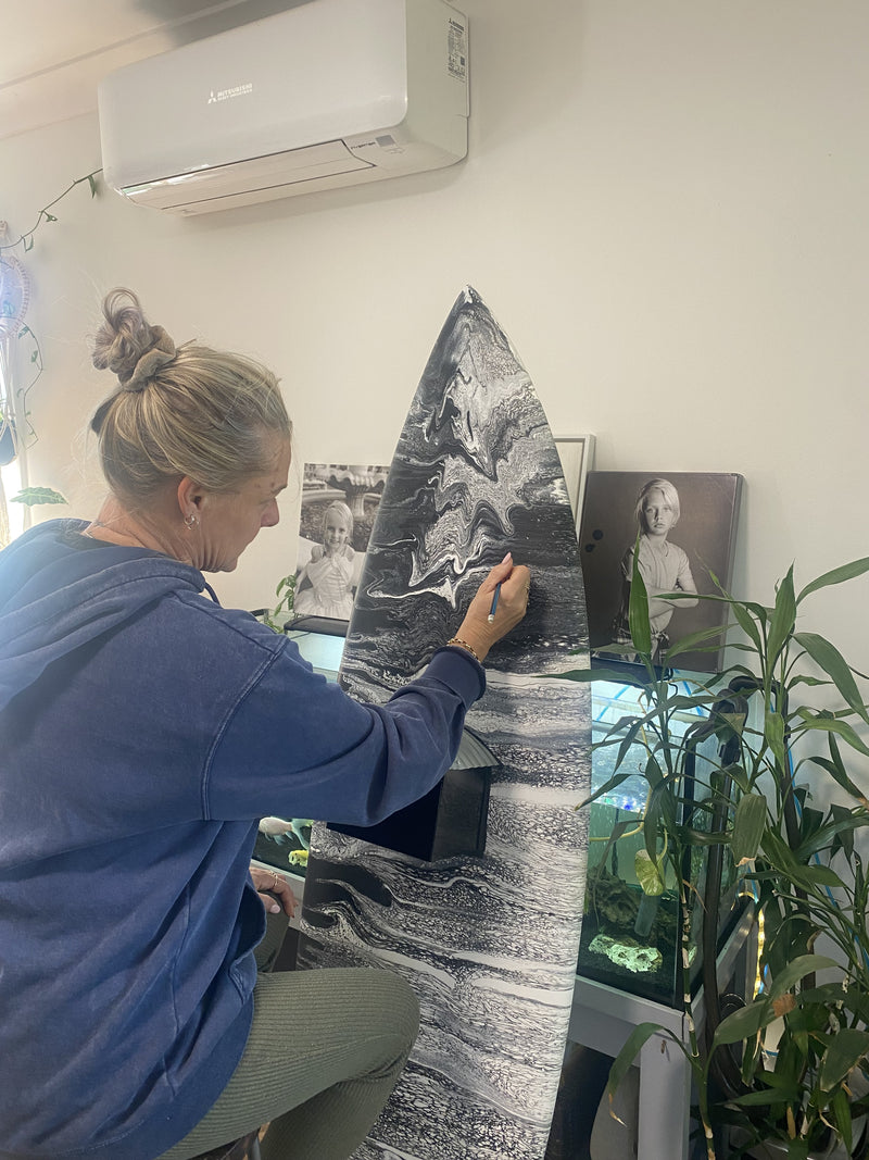 Kelly Stewart adding detail to an upcycled surfboard artwork