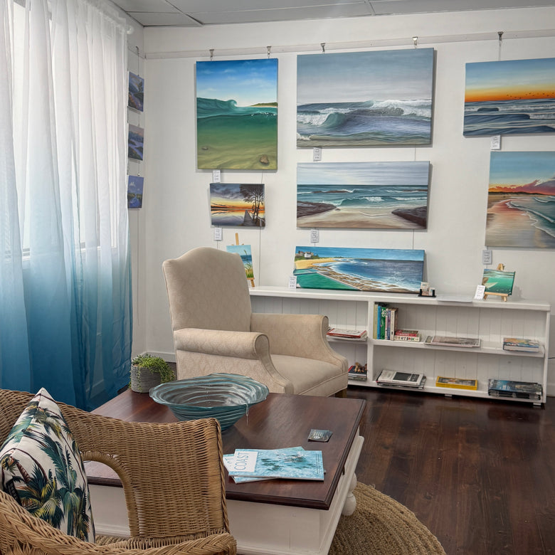 Art gallery room with a wall of framed artwork and a coffee table and comfortable chairs.