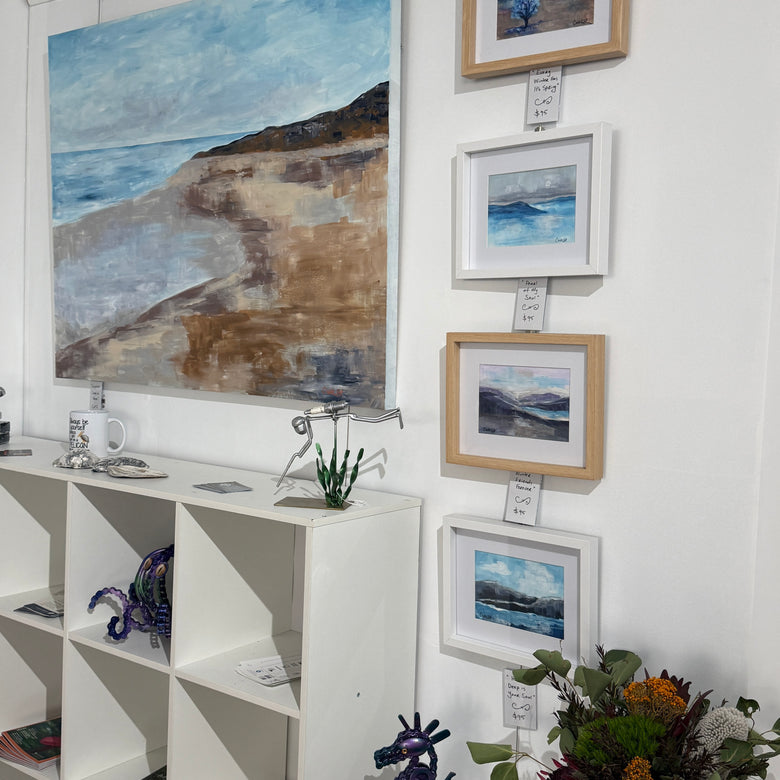 Artistic display of framed paintings and sculptures in a gallery setting.