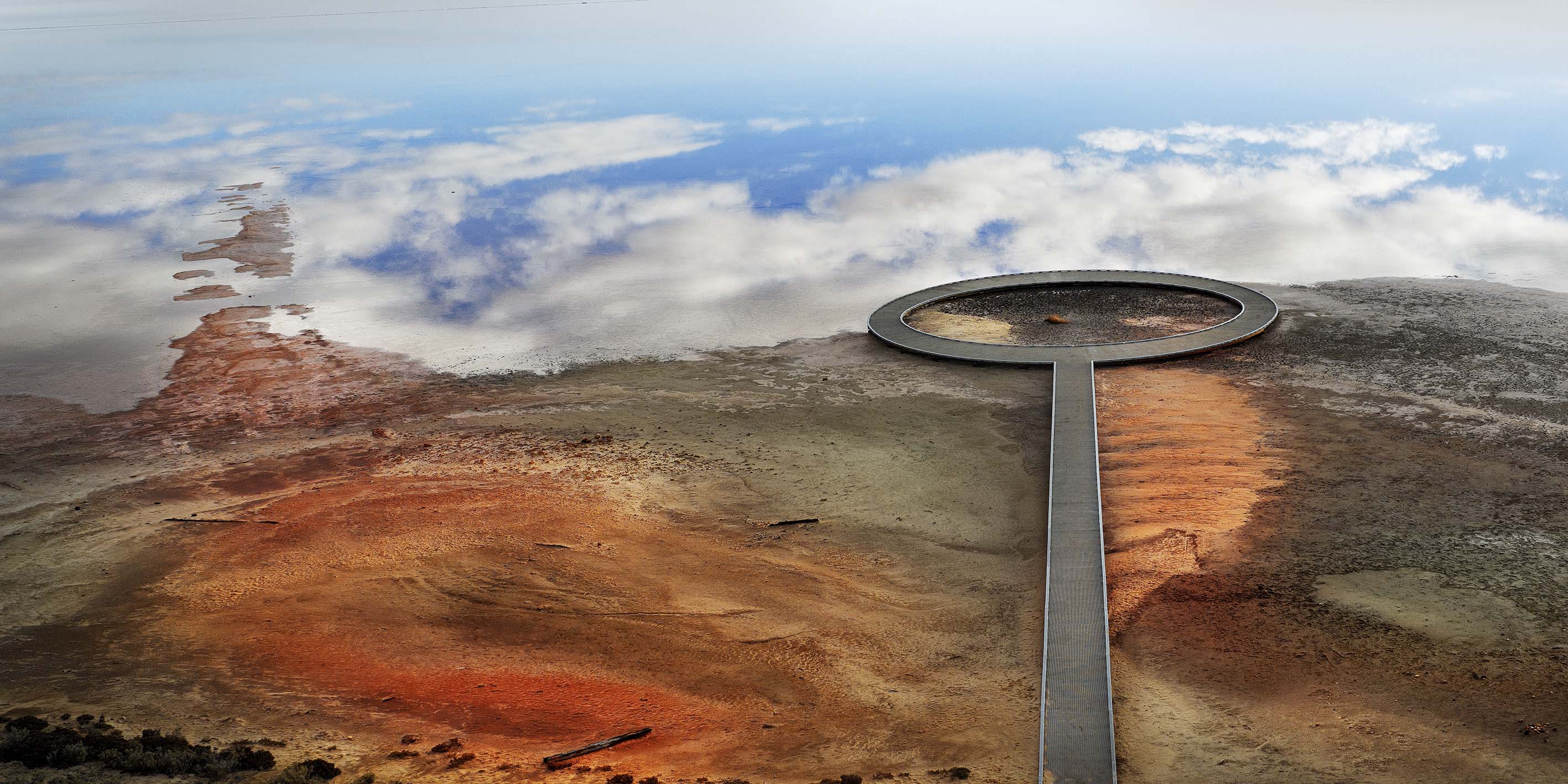 Circular metal boardwalk out to sky and clouds reflected in water at Lake Tyrell, salt lake in Victoria