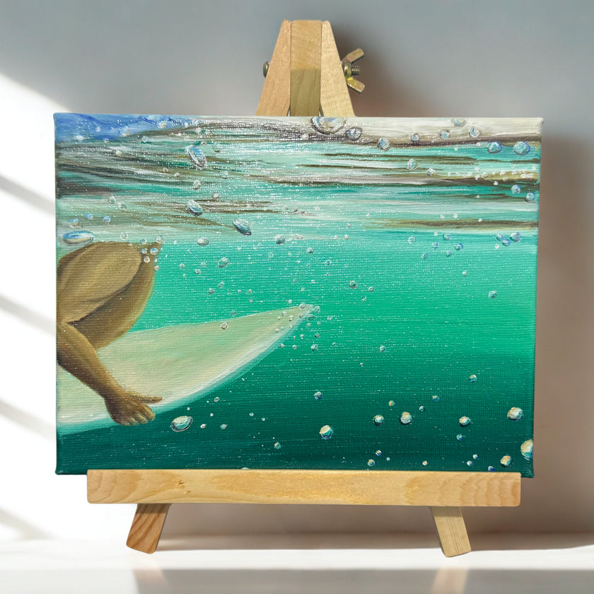 Underwater painting of a person on a surfboard on a wooden easel